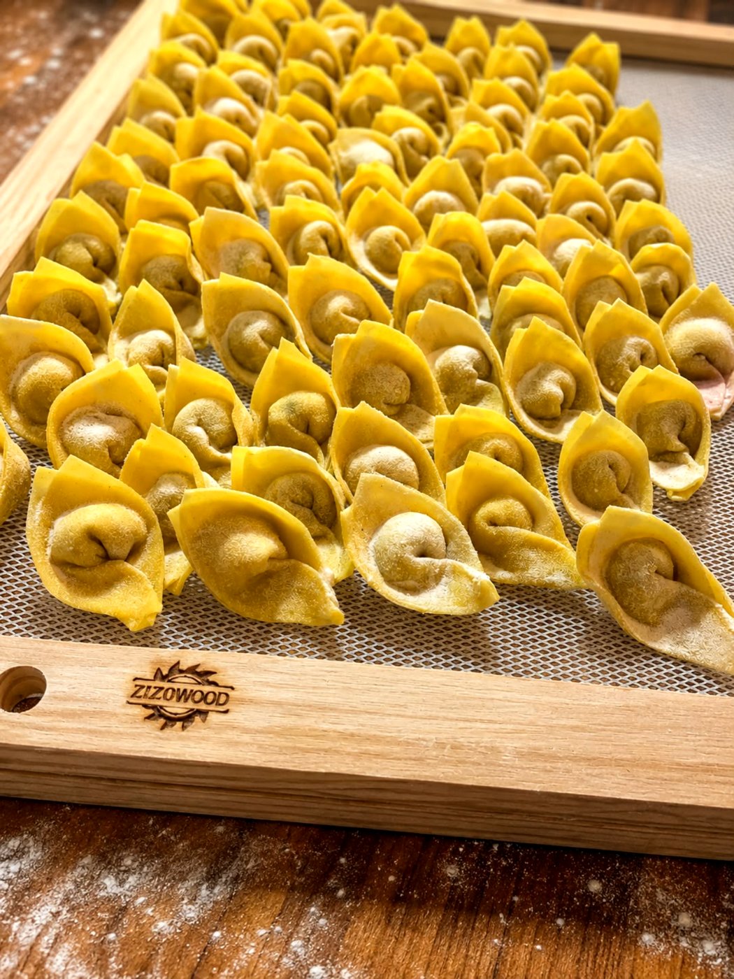 Tortelloni fechados um a um, secando em tábua de madeira
